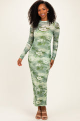 woman wearing a long sleeve green floral maxi dress with a fitted silhouette and a sheer overlay
