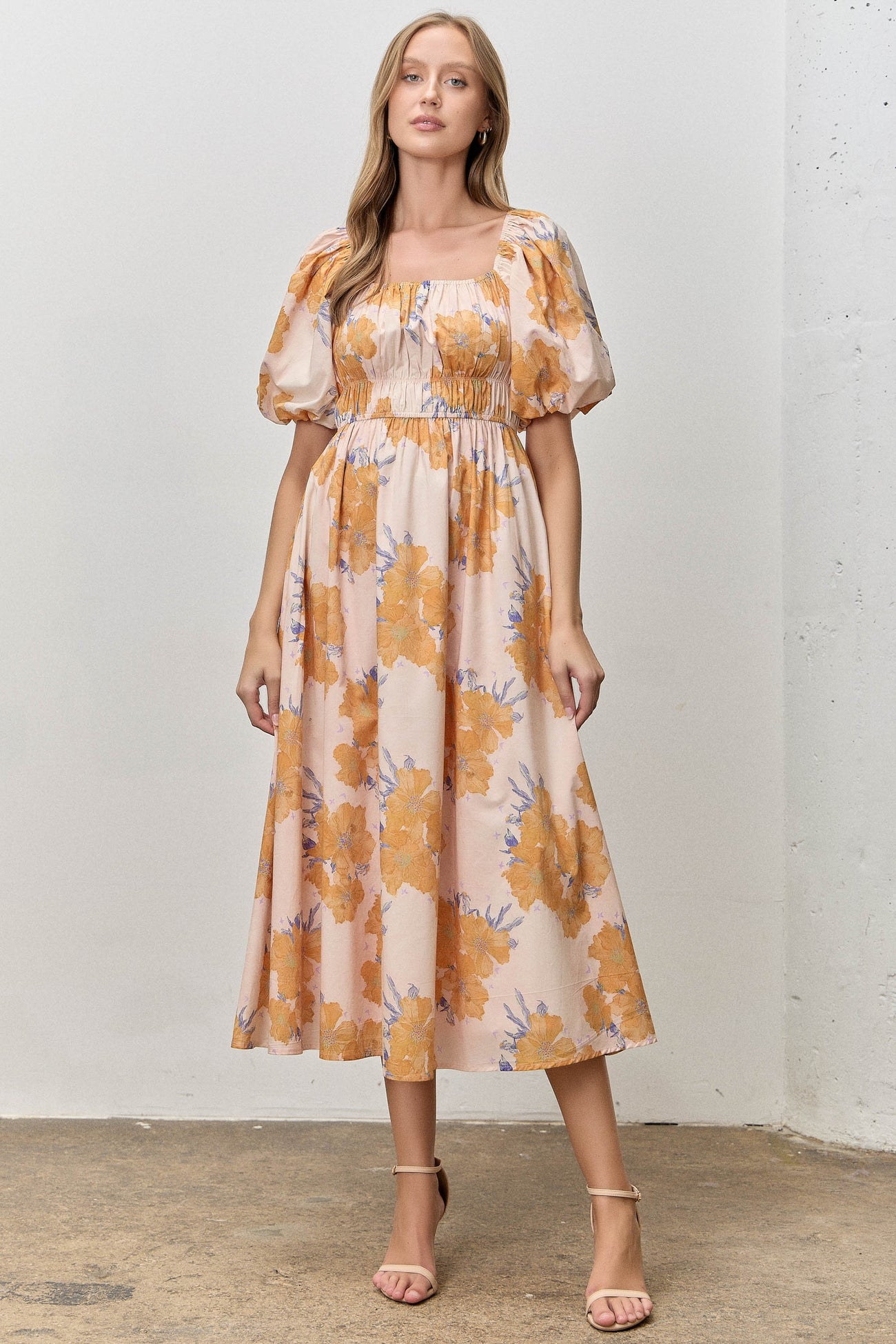 woman wearing a light pink floral midi dress with puff sleeves and a smocked bodice