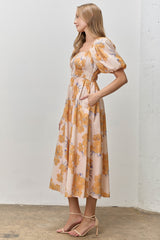 woman wearing a floral midi dress with puff sleeves and pockets in peach and orange tones