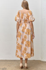 woman wearing a back view of a floral off-shoulder midi dress with puff sleeves in peach and orange tones
