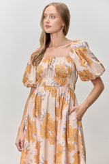 woman wearing a floral print midi dress with puff sleeves and a fitted bodice in peach and orange hues