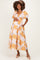 woman wearing a floral maternity dress with puff sleeves and smocked bodice, holding her baby bump