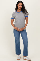woman wearing a gray and white striped maternity t-shirt with blue trim and holding her baby bump while standing in jeans