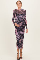 woman wearing a purple and black animal print maternity dress, holding her baby bump, with long sleeves and a fitted silhouette