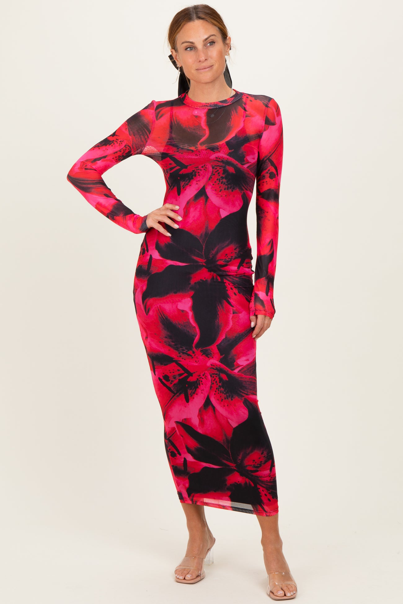 woman wearing a long sleeve fitted maxi dress with a red and black floral print