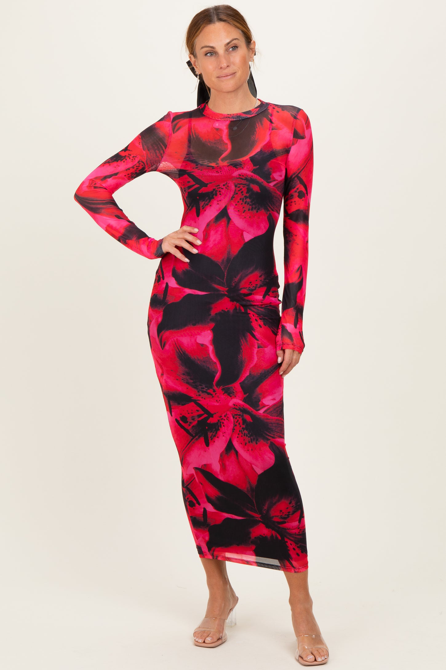 woman wearing a long sleeve fitted maxi dress with a red and black floral print