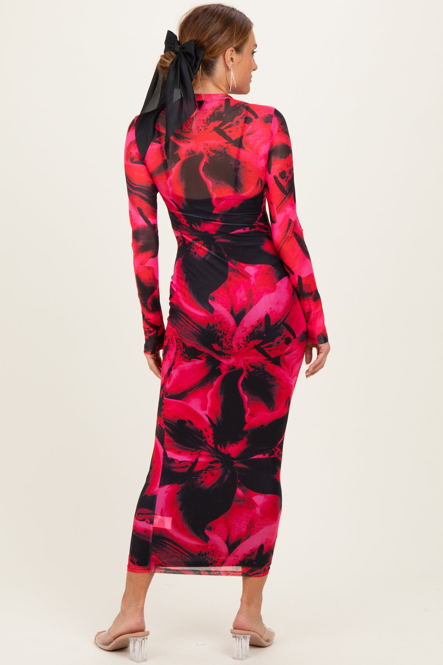 woman wearing a long sleeve pink and black floral print maxi dress with a back bow detail