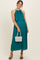 woman wearing a teal pleated maternity dress with a flowing top and holding a white beaded handbag, showing her baby bump
