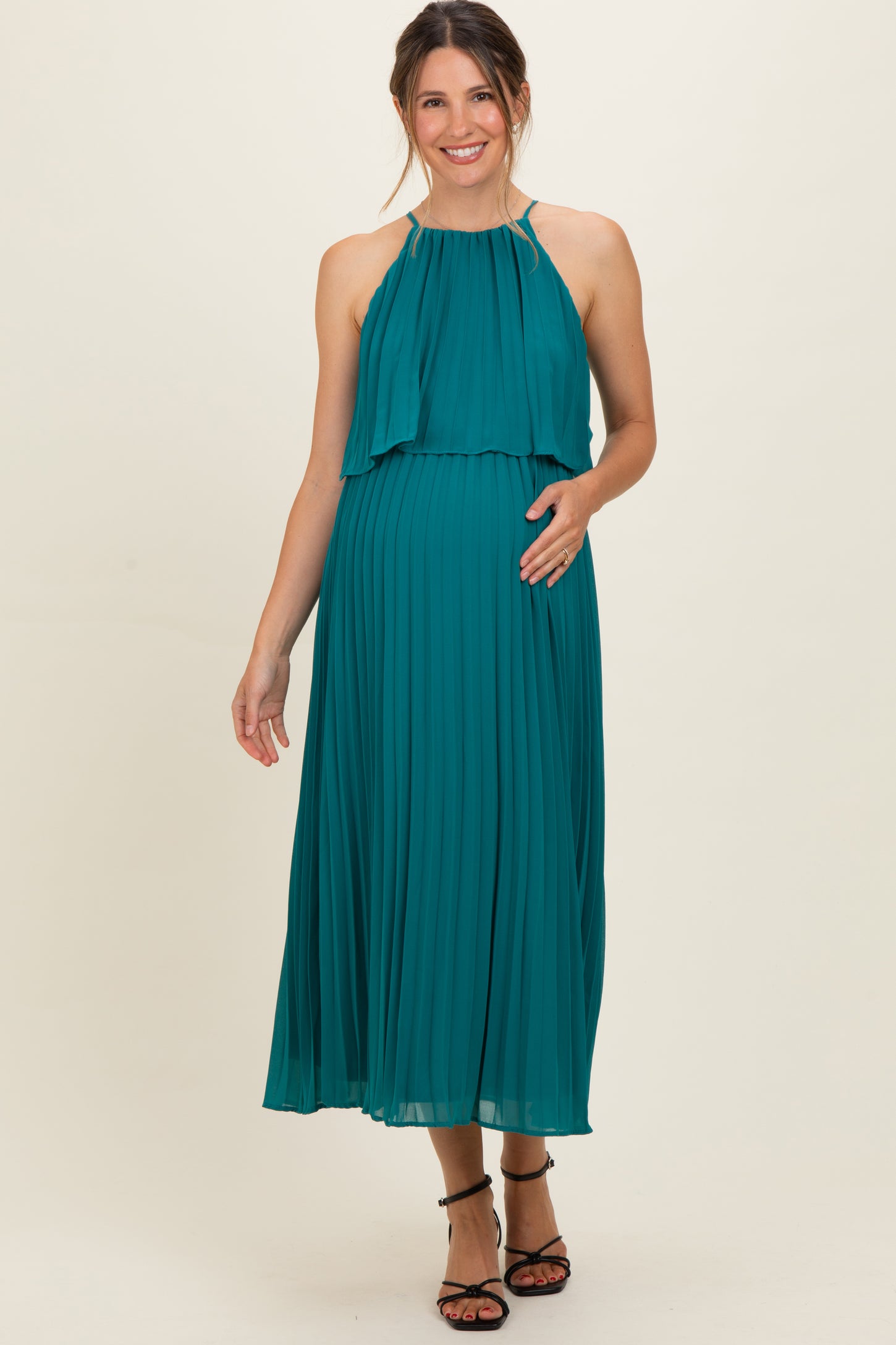 woman wearing a teal pleated maternity dress with halter neckline and baby bump visible
