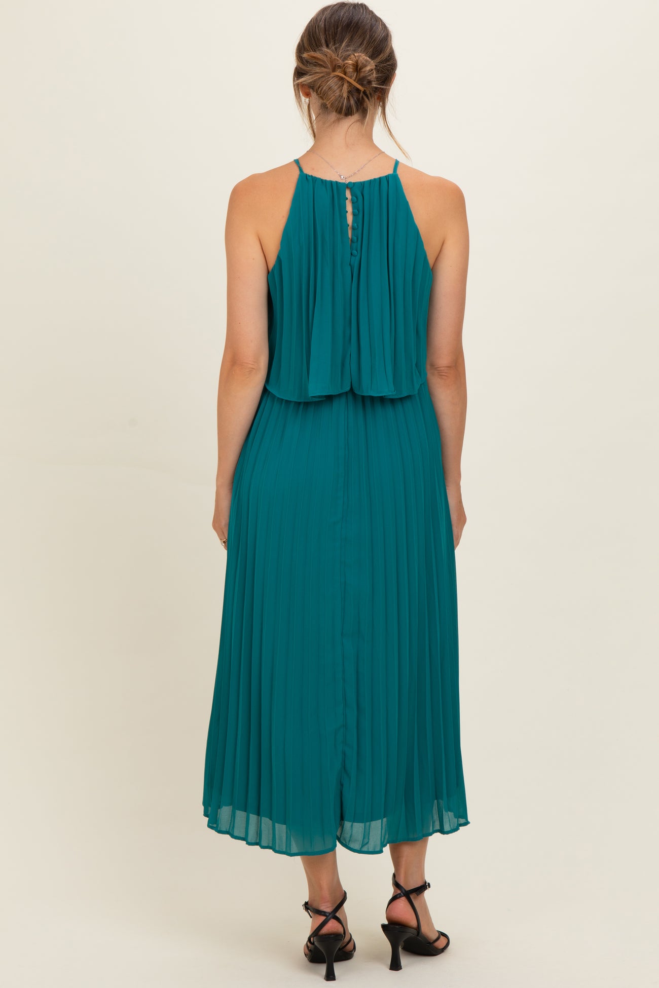 woman wearing a teal pleated maternity dress with a flowy back and adjustable straps
