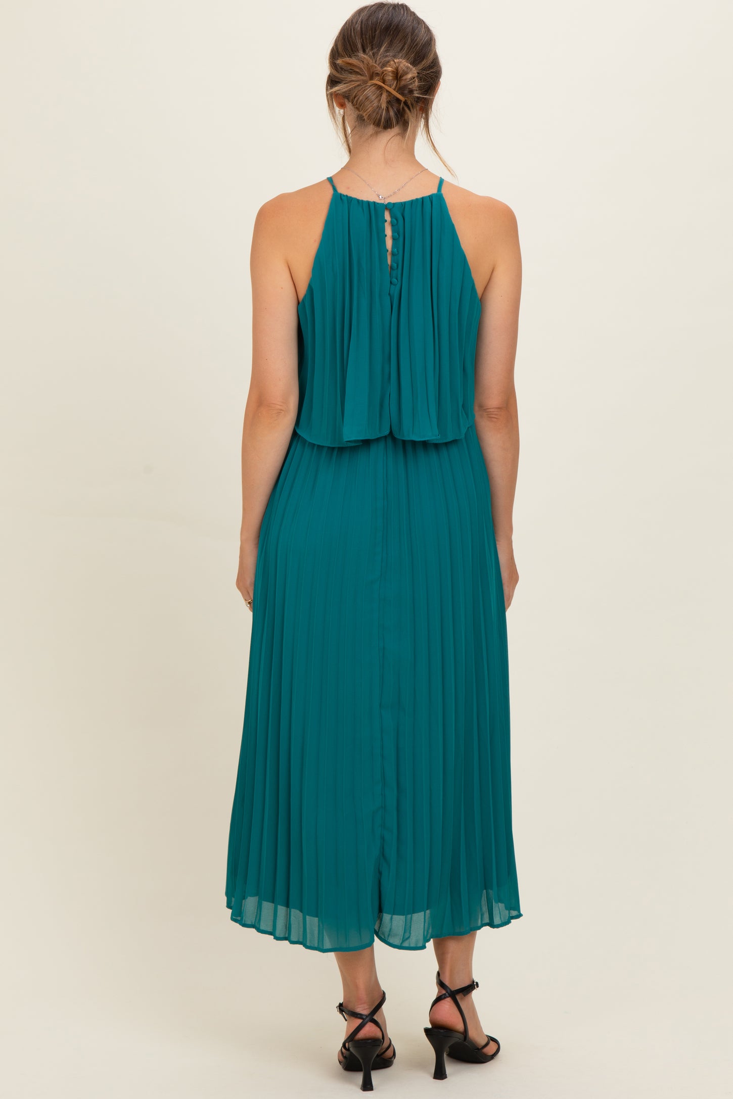 woman wearing a teal pleated maternity dress with a flowy back and adjustable straps