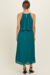 woman wearing a teal pleated maternity dress with a flowy back and adjustable straps
