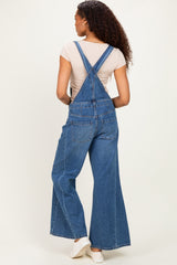 woman wearing a back view of a blue denim overall with wide legs and a fitted t-shirt underneath