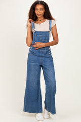 woman wearing a light gray short sleeve top with blue wide-leg denim overalls and white sneakers