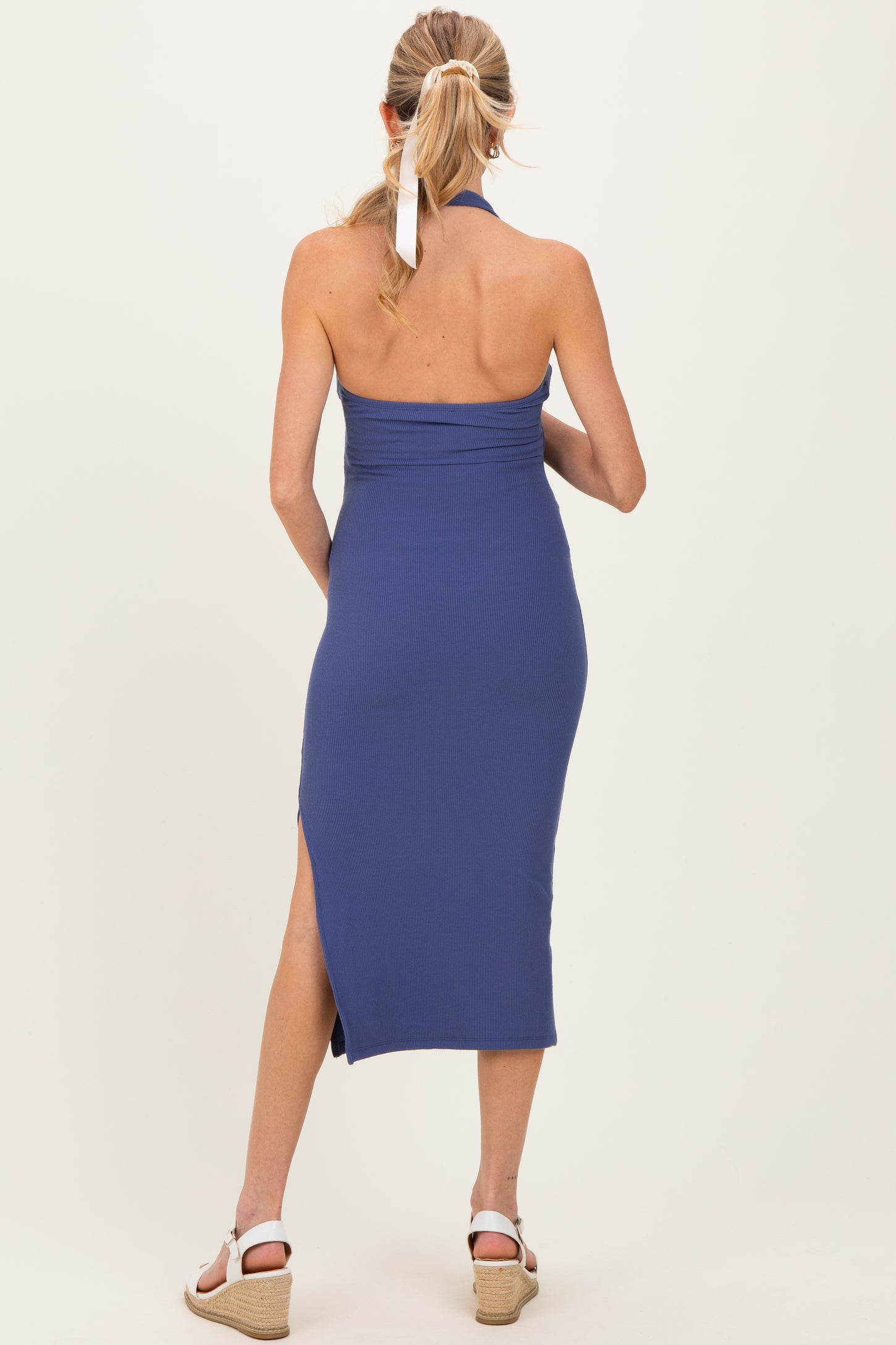 woman wearing a navy blue ribbed maternity dress with a halter neck and side slits