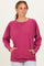woman wearing a pink oversized sweater with raglan sleeves and side pockets, styled casually with light wash jeans