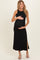 woman wearing a black sleeveless maternity dress with side slits and crinkled texture, holding her baby bump