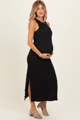 woman wearing a black sleeveless maternity dress with a side slit and holding her baby bump