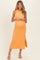 woman wearing a maternity orange textured midi dress with a side slit and a baby bump visible