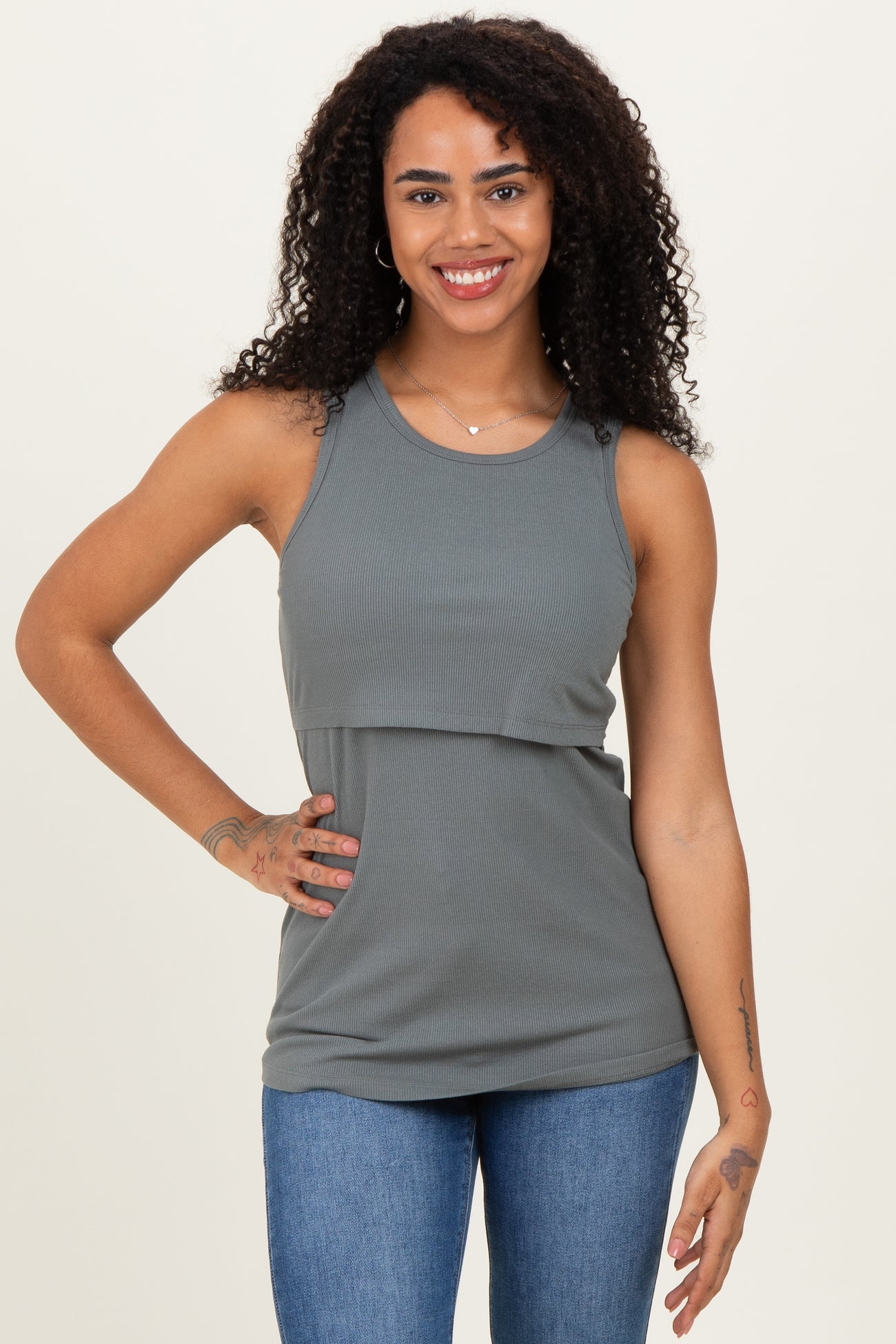 woman wearing a gray ribbed sleeveless top with a layered design and denim jeans