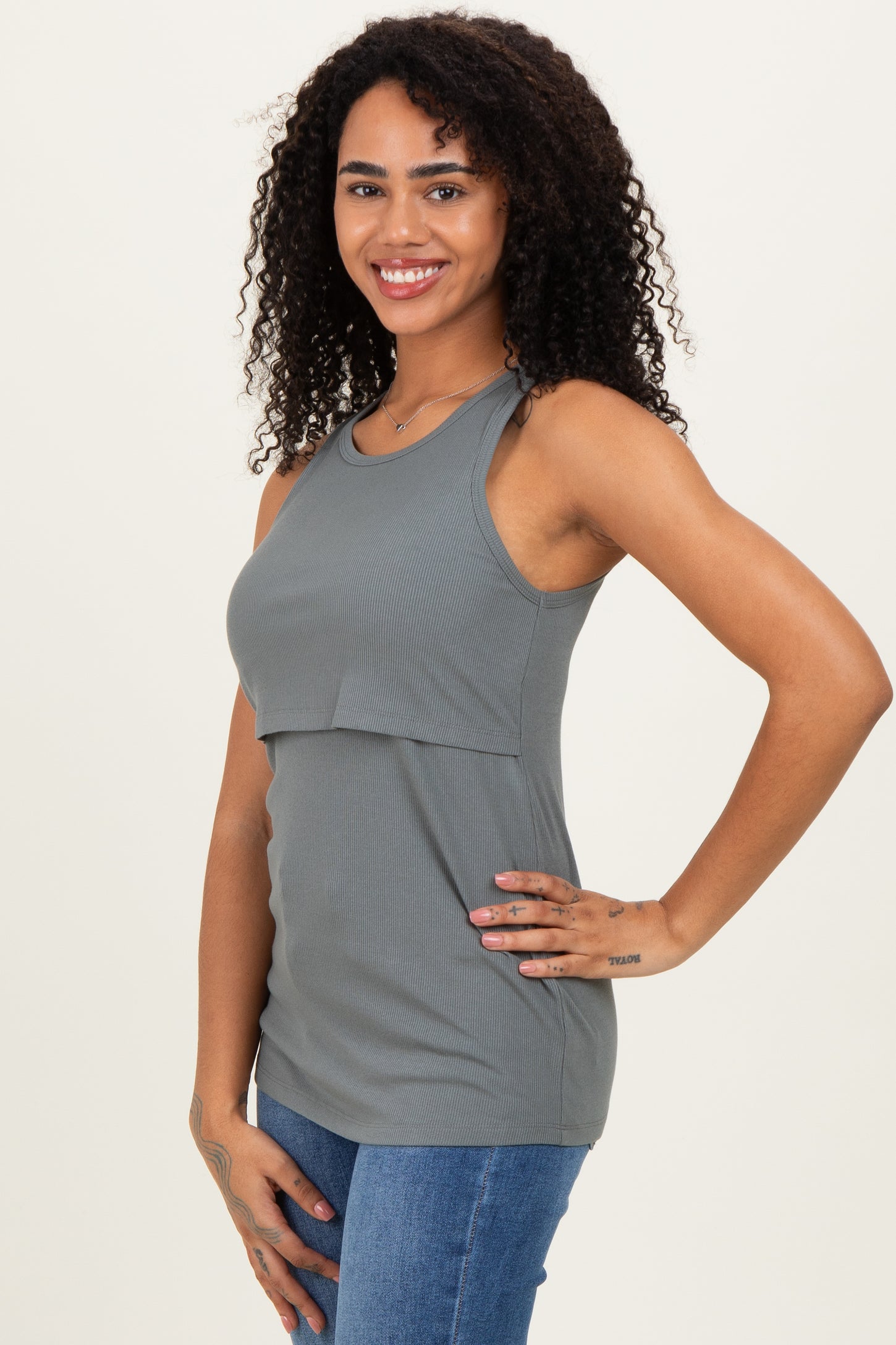 woman wearing a gray ribbed tank top with a layered design and styled with blue jeans