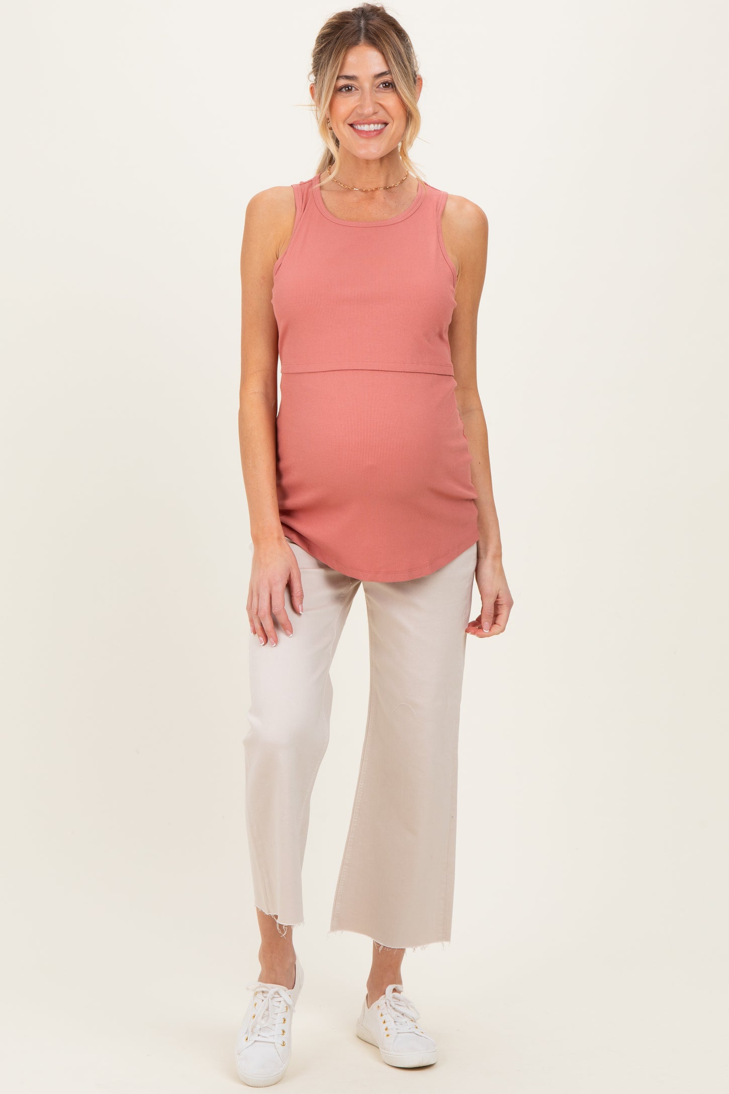 woman wearing a dusty rose ribbed maternity tank top and light beige cropped pants, showing her baby bump