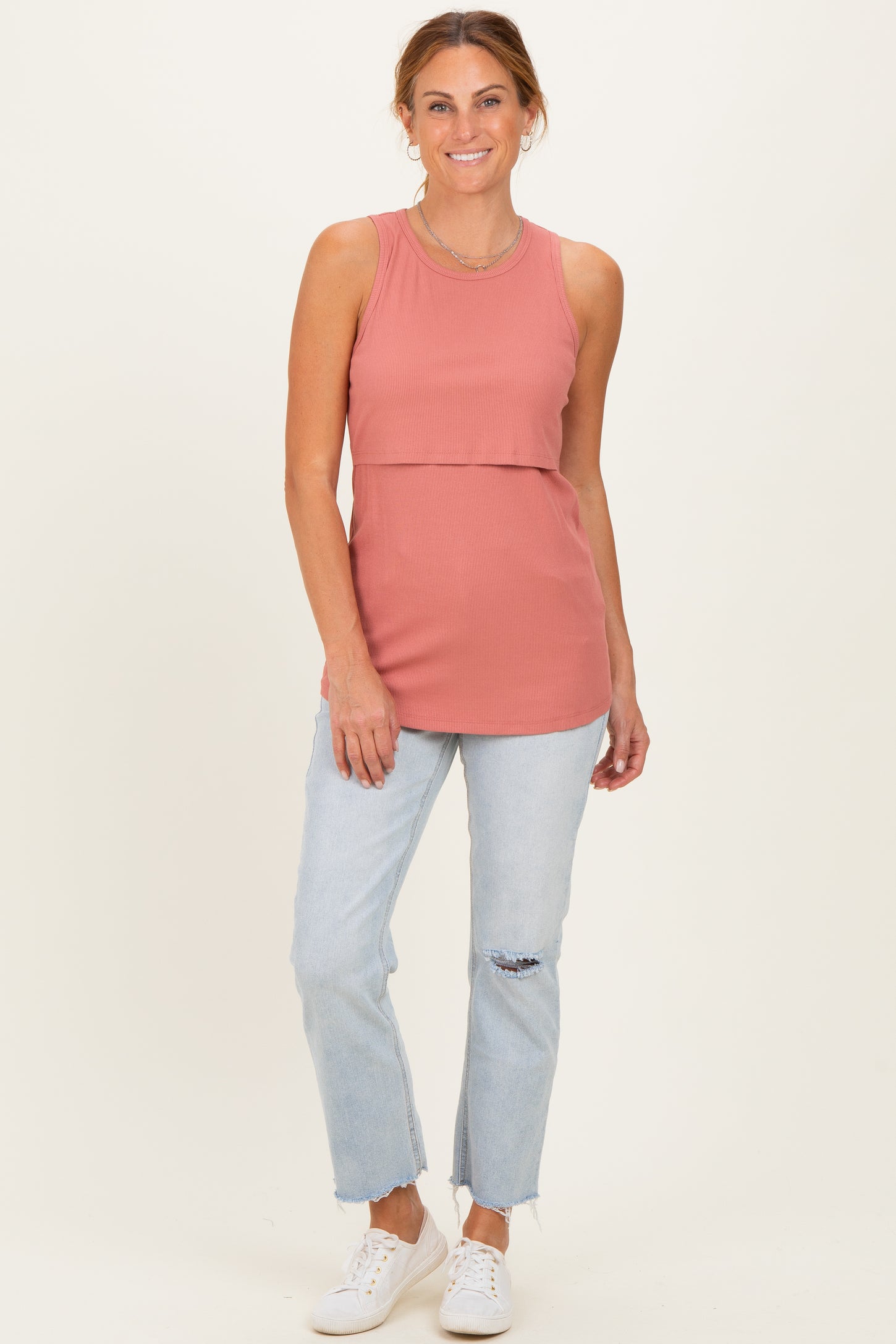 woman wearing a rust-colored ribbed sleeveless top with a layered effect and light blue distressed jeans