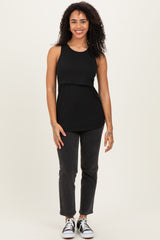 woman wearing a black sleeveless top and dark slim-fit jeans with sneakers, smiling at the camera