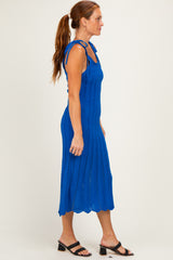 woman wearing a blue knitted midi dress with tie shoulder straps and a scalloped hem