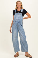 woman wearing light blue maternity overalls with wide-leg design, styled with a black t-shirt and sandals, smiling