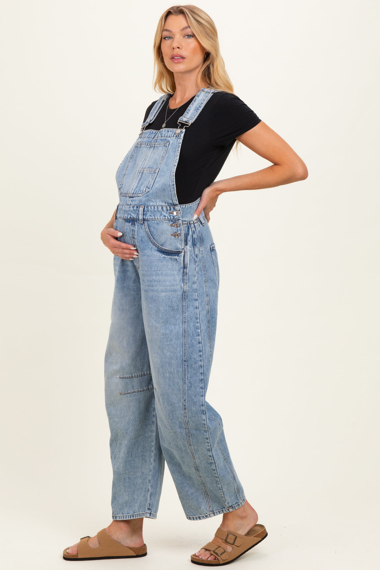 woman wearing light blue maternity overalls and a black t-shirt, showing her baby bump