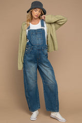 woman wearing blue denim maternity overalls with a white t-shirt and green cardigan, styled with a bucket hat