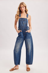 woman wearing a light blue denim overall with a loose fit and pockets, styled with brown sandals