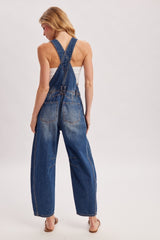 woman wearing a back view of a light blue denim overall with wide legs and crossed straps