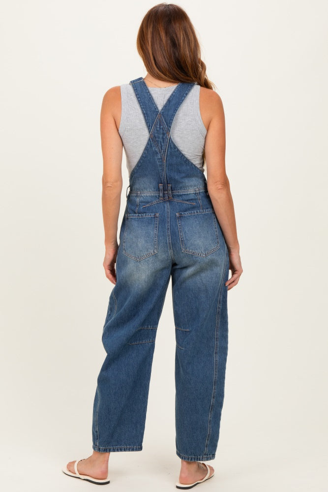woman wearing a gray tank top and blue denim overalls viewed from the back