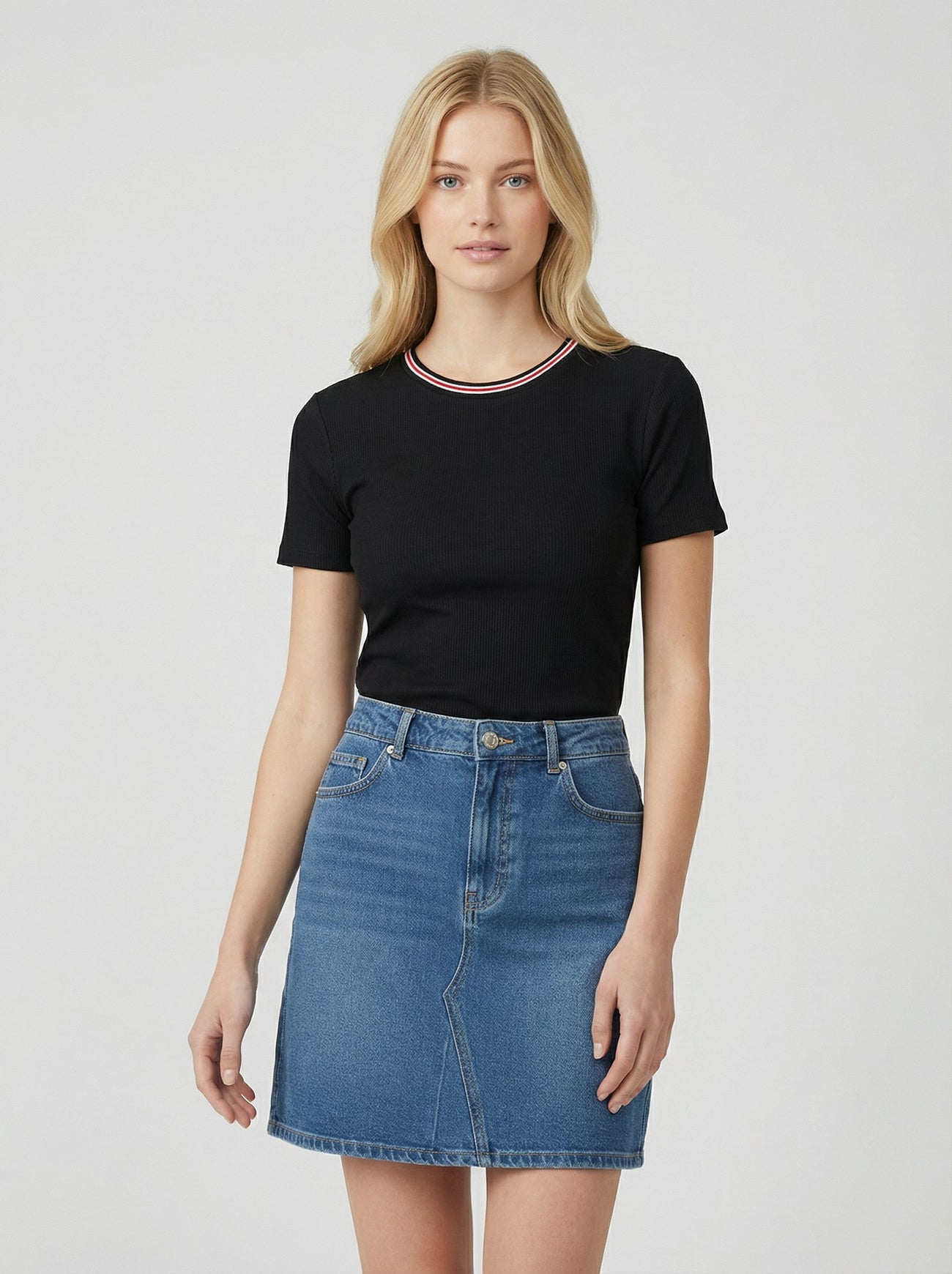 woman wearing a black short sleeve top with a red and white collar and a blue denim mini skirt