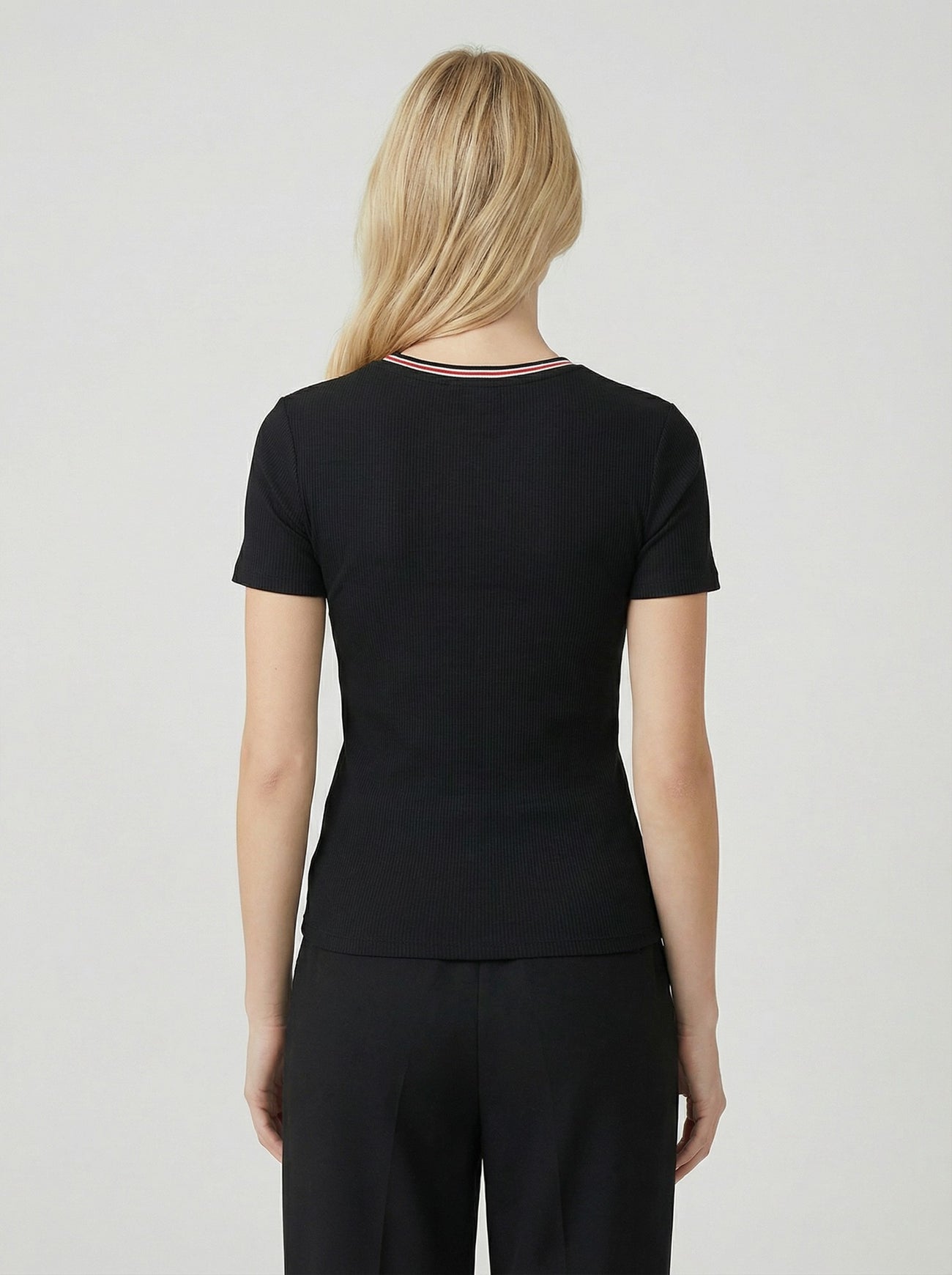 woman wearing a black ribbed short sleeve top, shown from the back, paired with black pants