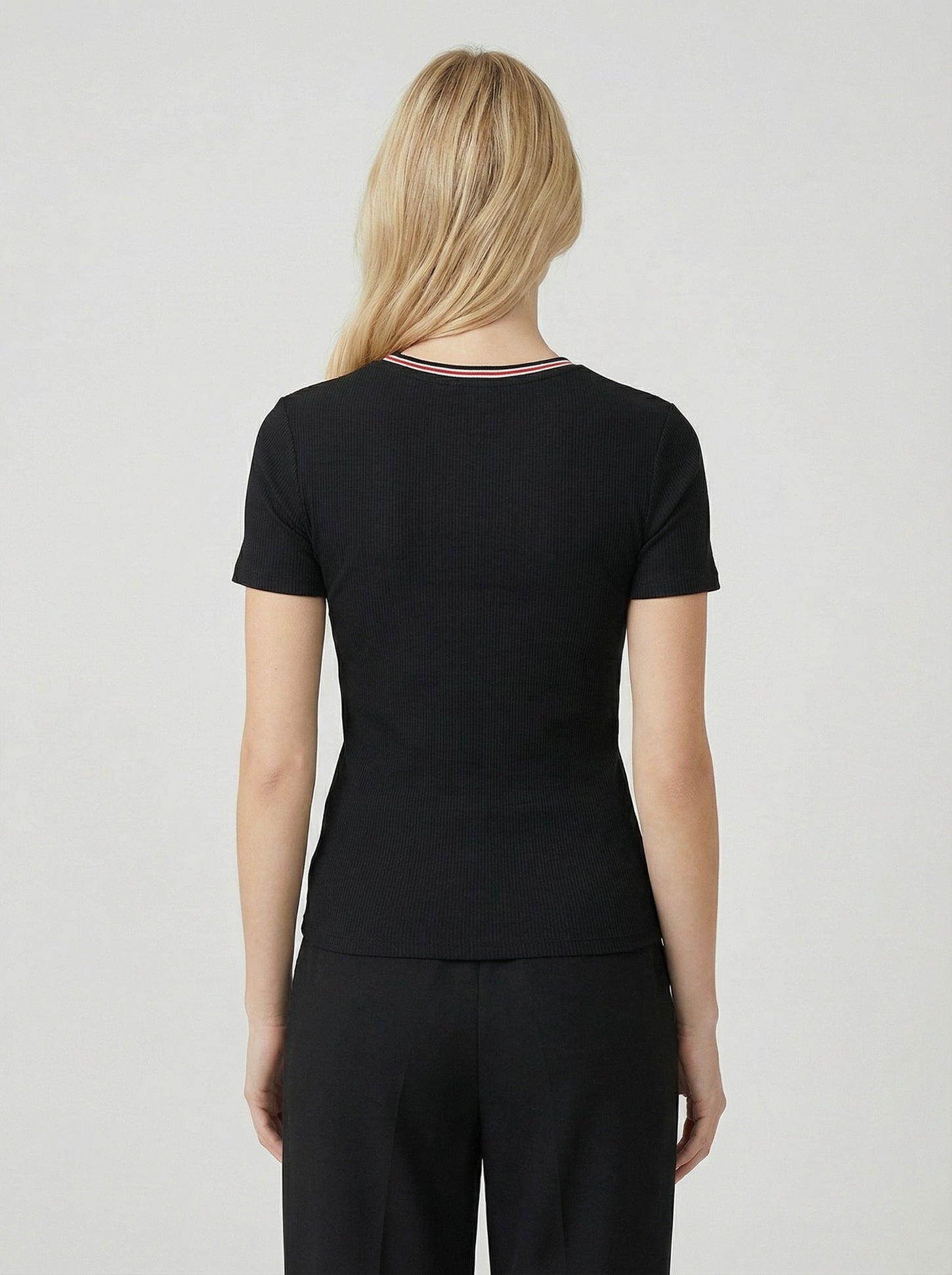 woman wearing a black ribbed short sleeve top, shown from the back, paired with black pants