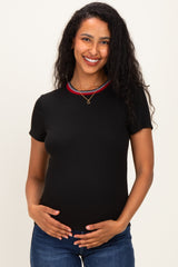woman wearing a black short sleeve maternity top with a red and white striped neckline and holding her baby bump