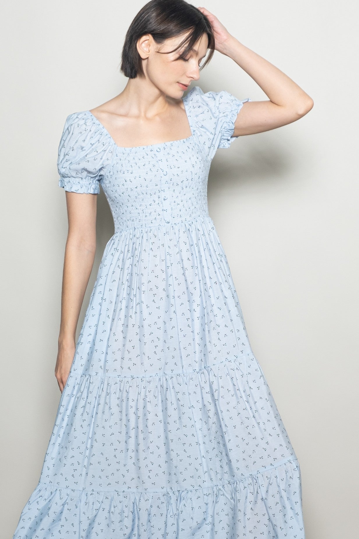 woman wearing a light blue square neck maxi dress with short puff sleeves and a tiered skirt