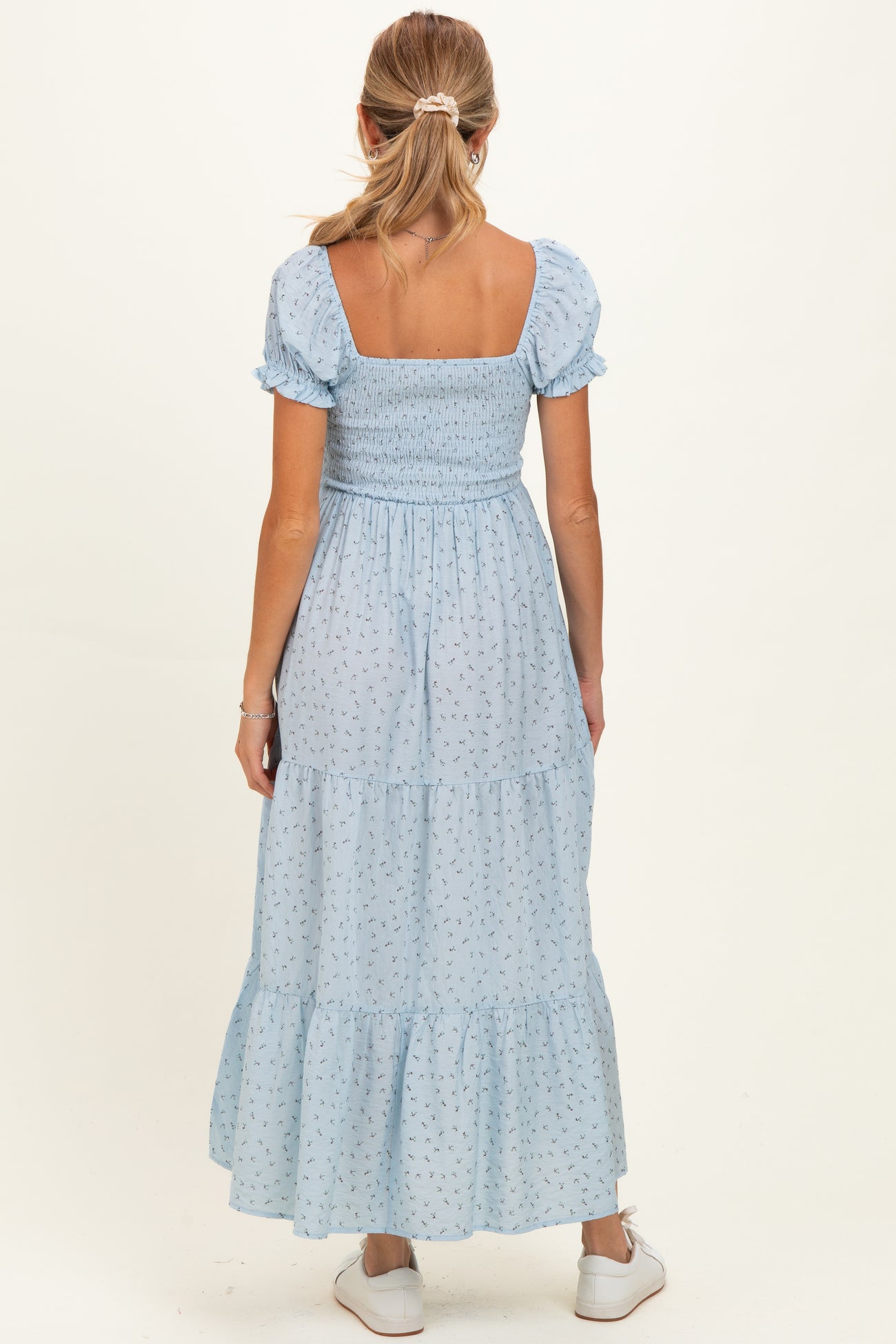 woman wearing a light blue maternity maxi dress with smocked bodice and puff sleeves, viewed from the back