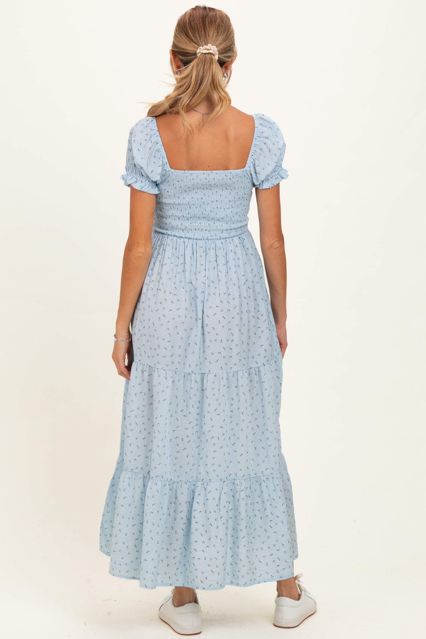 woman wearing a light blue maternity maxi dress with smocked bodice and puff sleeves, viewed from the back