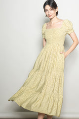 woman wearing a yellow floral print midi dress with puff sleeves and pockets