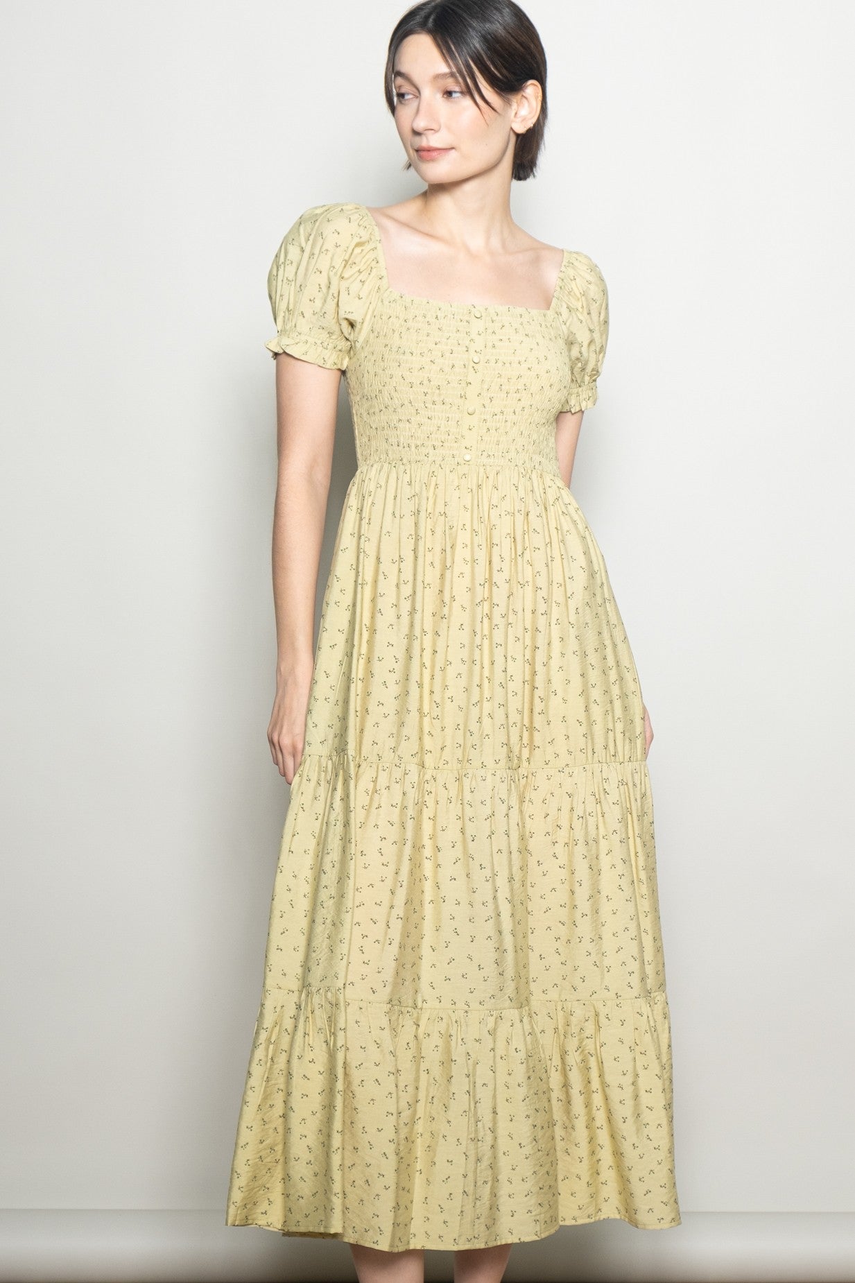 woman wearing a yellow floral print square neck maxi dress with puff sleeves and tiered skirt