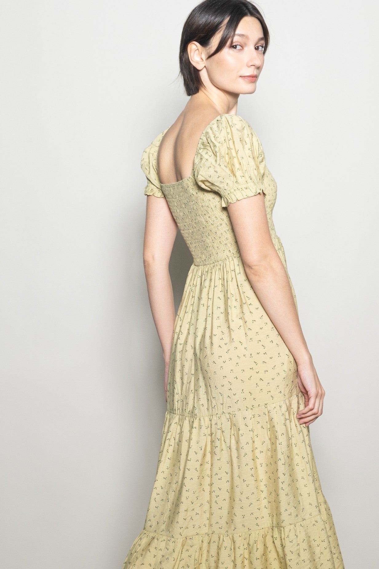woman wearing a yellow floral print puff sleeve maxi dress with a tiered skirt and fitted bodice