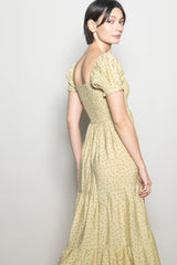 woman wearing a yellow floral print puff sleeve maxi dress with a tiered skirt and fitted bodice
