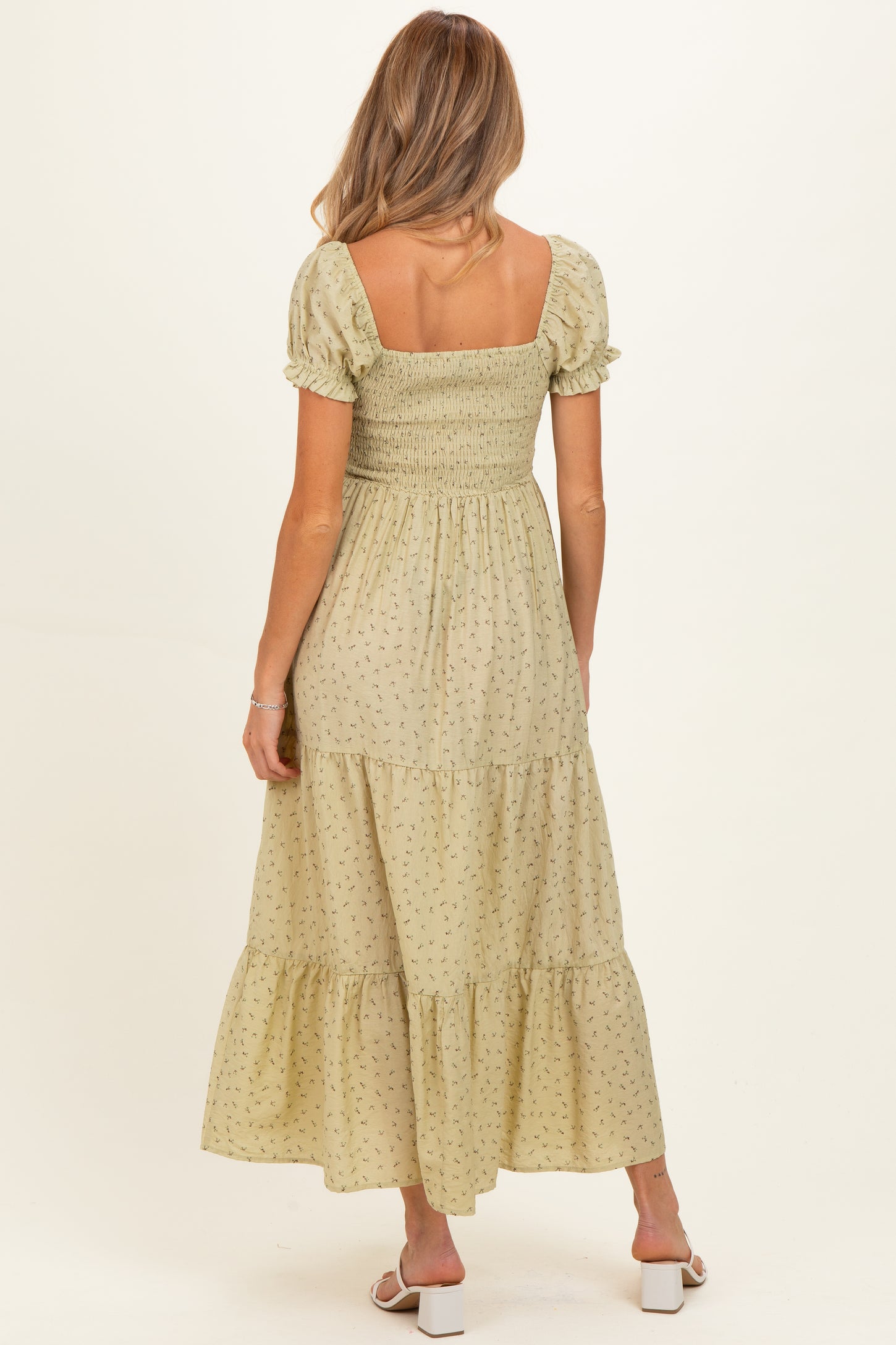 woman wearing a light yellow floral maternity maxi dress with a smocked bodice and puff sleeves, showing her baby bump