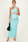 woman wearing a turquoise one-shoulder maternity dress, holding her baby bump and carrying a black handbag