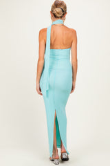 woman wearing a light aqua maternity dress with a halter neckline and a thigh-high slit, showing her back