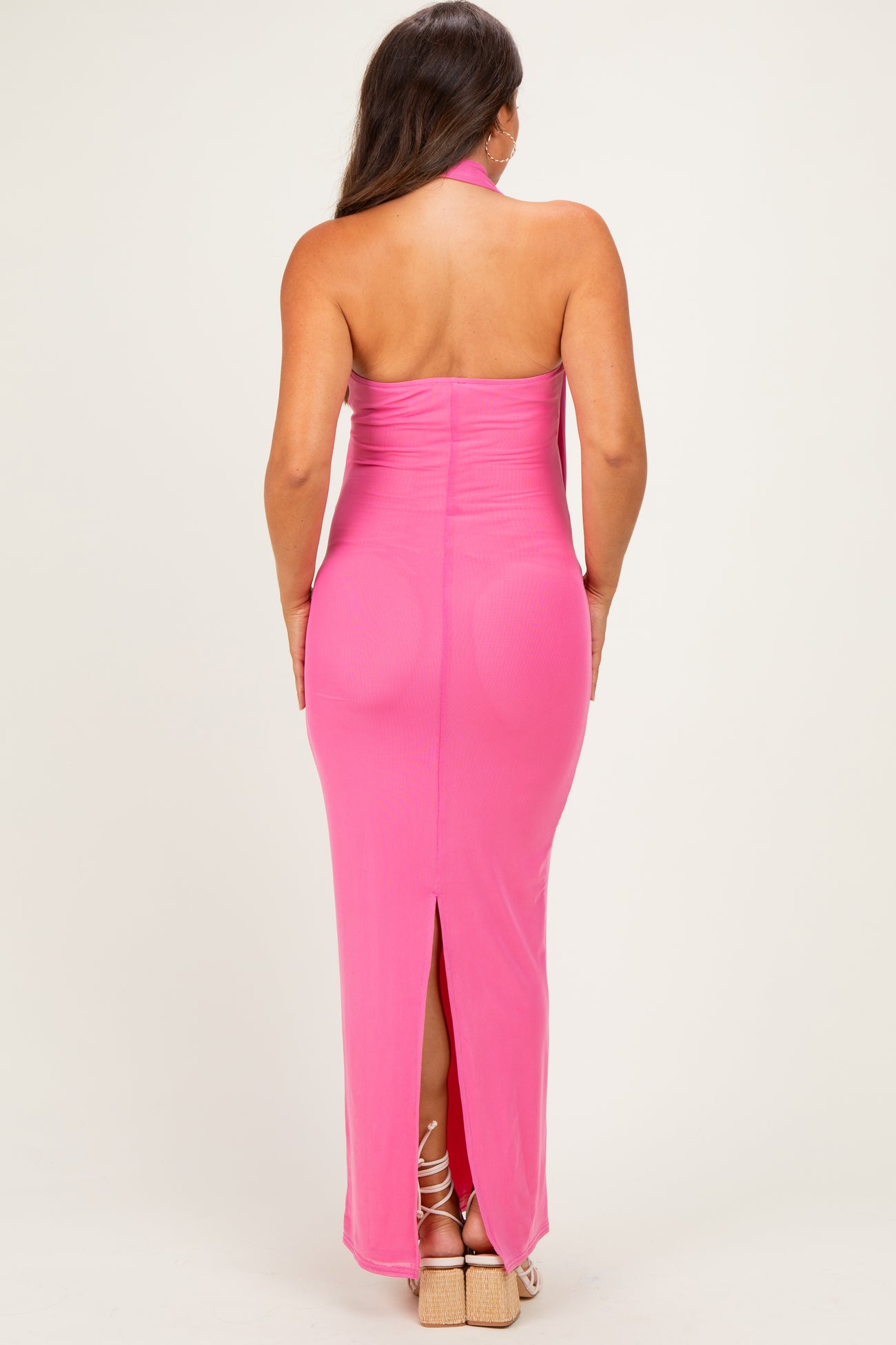 woman wearing a pink halter neck maternity gown with a back slit and body-hugging fit